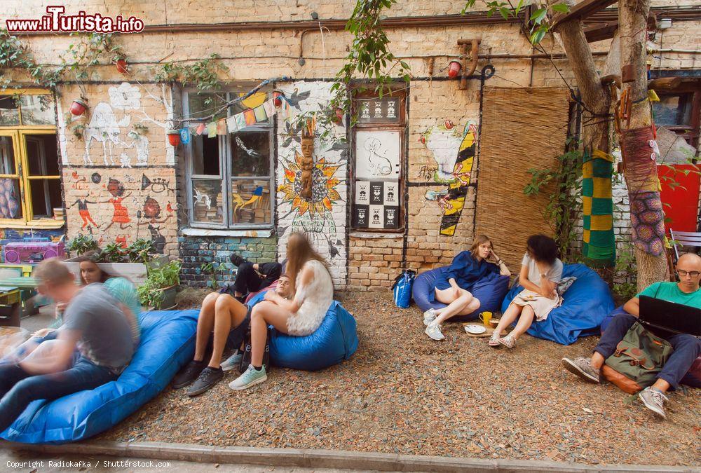 Immagine Giovani in relax nel dehors di un caffe a Kiev, Ucraina. Un gruppo di ragazzi seduti in comode poltrone in una piazzetta davanti a un locale. Kiev è l'ottava città più popolosa d'Europa - © Radiokafka / Shutterstock.com