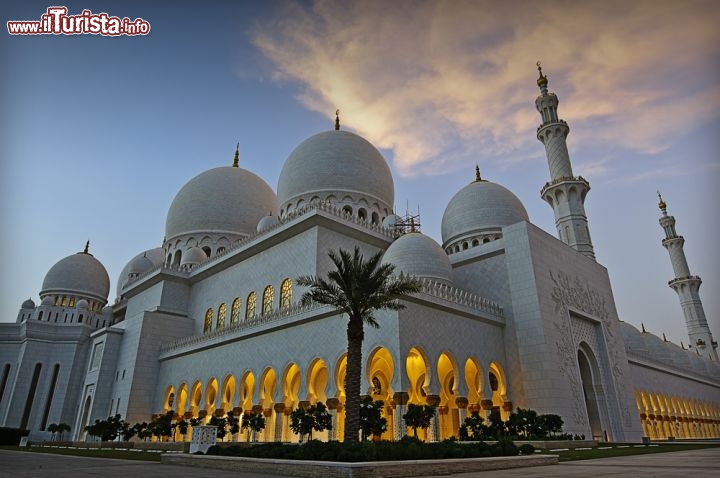 Immagine Al calar del sole la Grande Moschea Zayed si trasforma in una delle attrattive più affascinanti e romantiche di Abu Dhabi, capitale degli Emirati Arabi Uniti. Dalle 1000 colonne dei portici filtra la luce dell'interno, prodotta da centinaia di lampadari placcati in oro - © hainaultphoto / Shutterstock.com