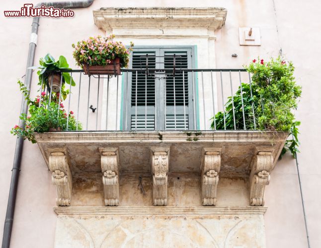 Immagine I dettagli barocchi di un balcone nel centro storico di Noto - Noto è stata definita più volte "la perfetta città barocca", è stata insignita del titolo di "patrimonio dell'umanità" proprio per il suo essere barocca, e non si può negare, che mai titolo fu più azzeccato. Il centro storico di Noto è a tutti gli effetti un patrimonio dell'umanità, un incredibile trionfo di uno stile barocco che non troneggia solo da cattedrali e palazzi, ma che si nota nelle piazze, negli angoli delle strade, nei balconi delle case. Una città che è il frutto della sua ricostruzione, che dopo il terribile terremoto che la investì nel 1693, risorse dalle sue ceneri, più bella e maestosa che mai, diventando una vera e propria principessa barocca. - © Roberto Lo Savio / Shutterstock.com