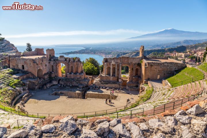 Immagine I resti del teatro greco di Taormina con l'Etna sullo sfondo, Sicilia. Scavato nella roccia, ha un diametro massimo di 109 metri e un'altezza di circa 20 metri. Il fondo della scena, di epoca romana e parzialmente aperto al centro, è delimitato da un muro su cui sono state collocate delle statue in marmo per spiegare come avrebbe dovuto essere la costruzione in origine. Attualmente, questa struttura può ospitare 4500 posti a sedere.
