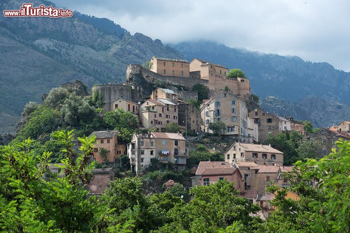 Immagine Le montagne avvolte dalle nuvole fanno da sfondo a Corte, storico borgo nell'entroterra della Corsica - tra vallate, ghiacciai e foreste di abeti e castagni, si trova Corte, storico borgo dove il turista può assaporare la vera anima della Corsica, fatta di musica per le strade, di piazze nascoste dal sapore antico, di mercatini di prodotti tipici tra vecchie case di pietra e paesaggi mozzafiato. Una meta irrinunciabile per chi desidera vivere questa splendida isola nella sua forma più autentica e tradizionale. 