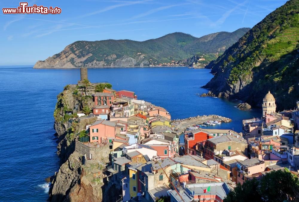 Immagine Il borgo marinaro di Vernazza nelle Cinque Terre, Liguria. Circondato da vegetazione lussureggiante e mare cristallino, offre un panorama mozzafiato.