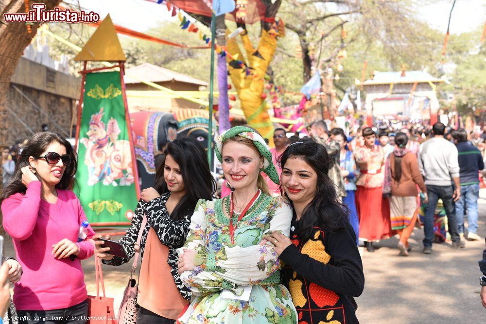 Immagine Il carnevale internazionale dei mestieri a Surajkund, Punjab, India. Due ragazze in posa per una fotografia con un'artista in abiti tradizionali - © singh_lens / Shutterstock.com