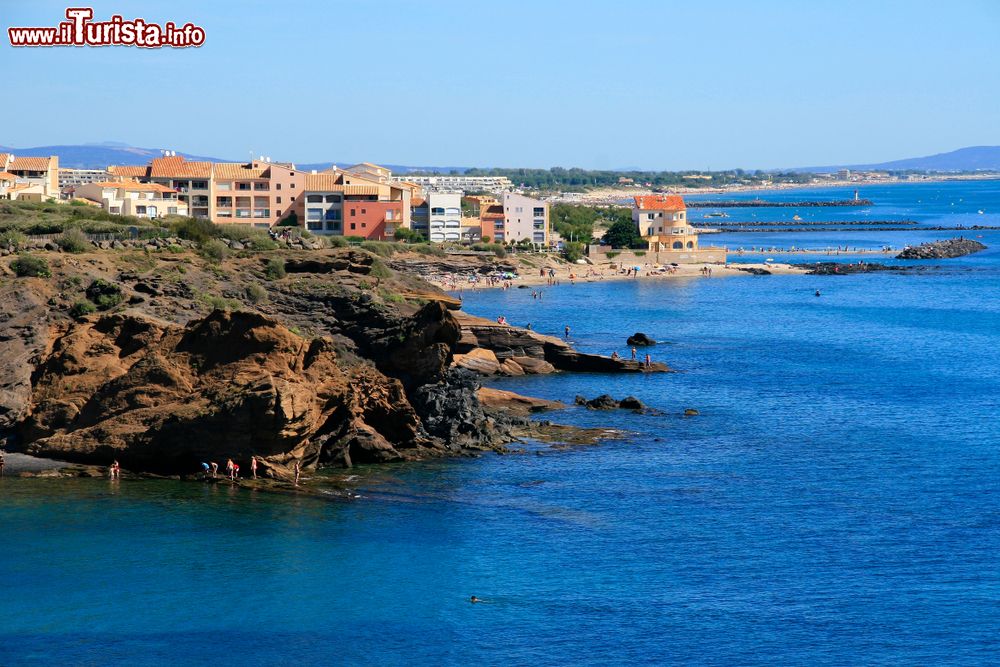 Immagine Il litorale roccioso di Cap d'Agde, Francia, con edifici residenziali sullo sfondo.