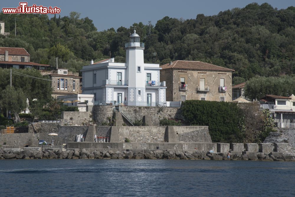 Immagine Il pittoresco faro del villaggio di Scario, provincia di Salerno, Campania. Attivato nel 1883, questo faro sorge in località Tragara fra alcune abitazioni d'epoca che si rispecchiano nell'acqua. E' uno dei simboli della cittadina.