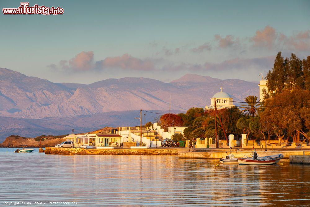 Immagine Il porto dell'isola di Inousses (Grecia) con un tratto di litorale. Sullo sfondo, uno degli antichi edifici religiosi - © Milan Gonda / Shutterstock.com