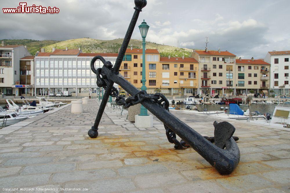 Immagine Il porto di Senj, Croazia, con le barche ormeggiate, e in primo piano il monumento a un ancora - © Wojciech Tchorzewski / Shutterstock.com