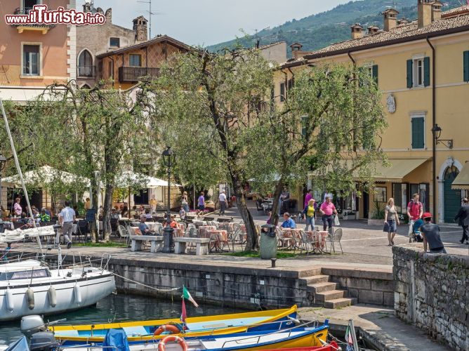 Immagine Il vecchio porto di Torri del Benaco, provincia di Verona. Sullo sfondo, uno scorcio del centro storico con edifici e turisti - © 167880122 / Shutterstock.com