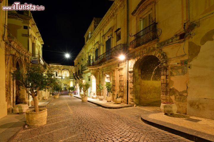 Immagine Immagine notturna di una via del centro storico di Noto - le luci della notte mettono in grande risalto gli splendidi e caldi colori che caratterizzano la città di Noto, la cui ricostruzione dopo il terremoto del 1693, avvenne per mezzo della pietra locale, di un colore tra l'ocra e il rosato.  Questa grande opera di ricostruzione della città, venne perpetrata in maniera talmente coerente e continua all'insegna del barocco, da essere considerata una città "perfetta" per quanto riguarda l'utilizzo di questo stile.  - © MaRap / Shutterstock.com