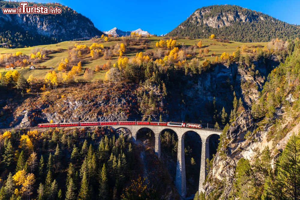 Immagine L'ingresso del Glacier Express nel tunnel del viadotto di Landwasser, Svizzera, con il suggestivo foliage autunnale degli alberi. Il primo Glacier Express partì il 25 giugno 1933 con 70 passeggeri a bordo e arrivò a St-Moritz 11 ore più tardi.
