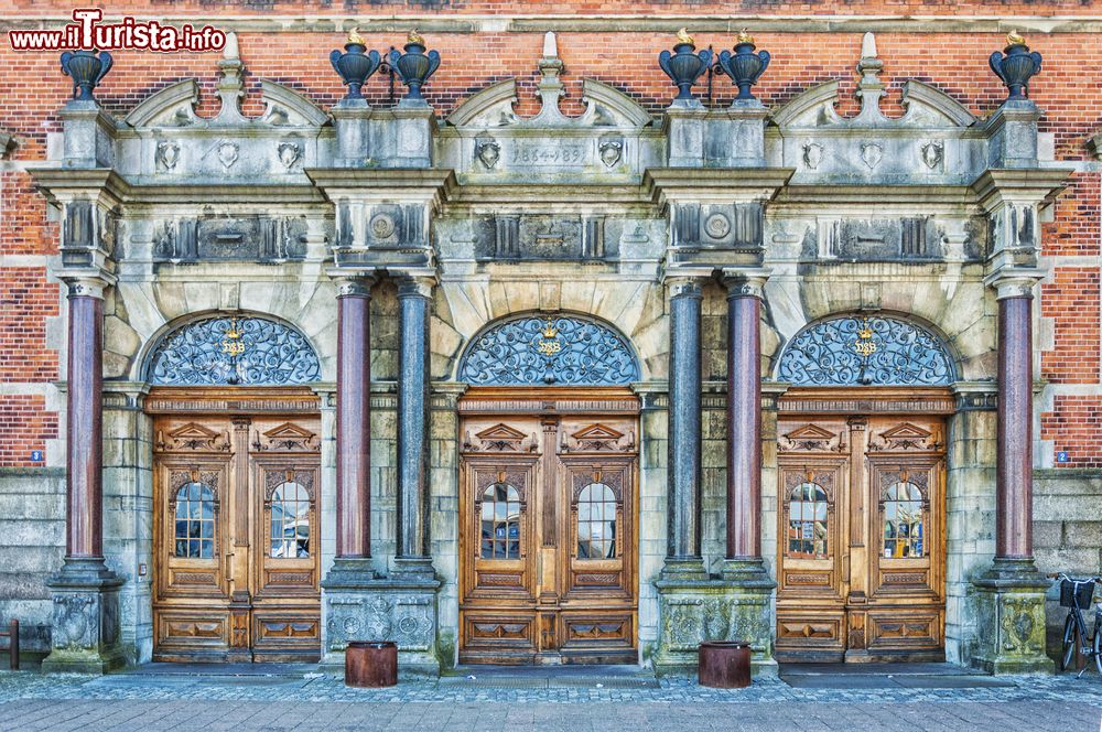 Immagine Ingresso principale alla stazione ferroviaria di Helsingor, Danimarca. Le tre porte in legno sono contornate da decorazioni e colonne.