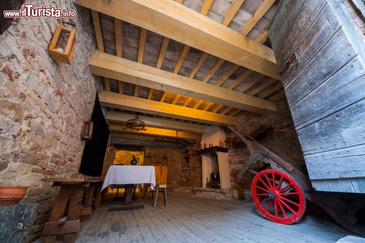 Immagine L'interno di un vecchio edificio a Gradara, Italia. Muri in pietra e pavimento in legno rendono ancora più suggestiva l'atmosfera di questo ambiente impreziosito dalla presenza del camino e di un antico carretto per il trasporto