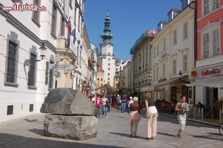 Immagine Torre di San Michele e via Michalska a Bratislava, Slovacchia - Delle 4 porte d'accesso fortificate medievali che permettevano l'ingresso dalle mura della città di Bratislava solo la Torre di San Michele è giunta sino ai giorni d'oggi. Iniziata nel XIV° secolo, la sua edificazione subì vari interventi di rifacimento soprattutto fra il 1511 e il 1517 con la trasformazione della parte superiore in una costruzione ortogonale e quello di metà diciottesimo secolo che la dotò di una cupola in rame barocca a forma di turbante sulla cui cima svetta la statua di San Michele Arcangelo in rame con un drago.