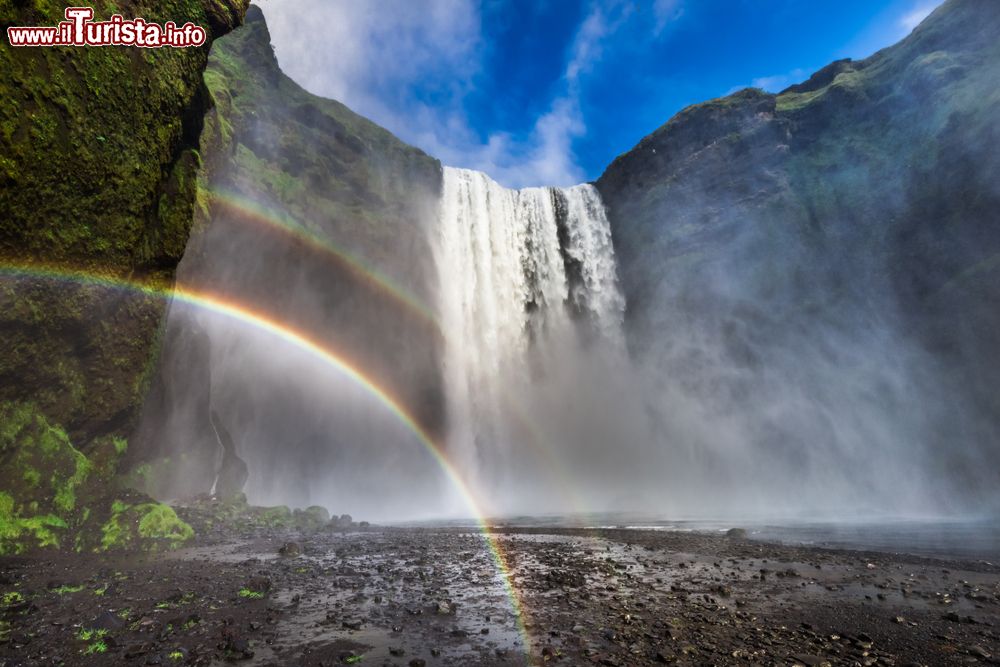 Immagine La cascata di Skogafoss con l'arcobaleno, Islanda. Situata nel sud dell'isola vicino alla località di Skogar, è originata dal fiume Skogaa: è alta 60 metri e alta 25. Sul lato destro del salto s'inerpica una scalinata di 700 gradini che porta sino quasi in cima.