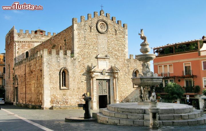 Immagine La cattedrale di San Nicola con la fontana a Taormina, Sicilia. Chiesa di architettura medievale dedicata a San Nicola di Bari, il duomo di Taormina si trova lungo corso Umberto nei pressi di Porta Catania. Soprannominata "cattedrale fortezza" per la sua austerità, questa chiesa si presenta con una facciata caratterizzata da merlatura a corona. Di particolare pregio è il portale principale restaurato nel 1936.