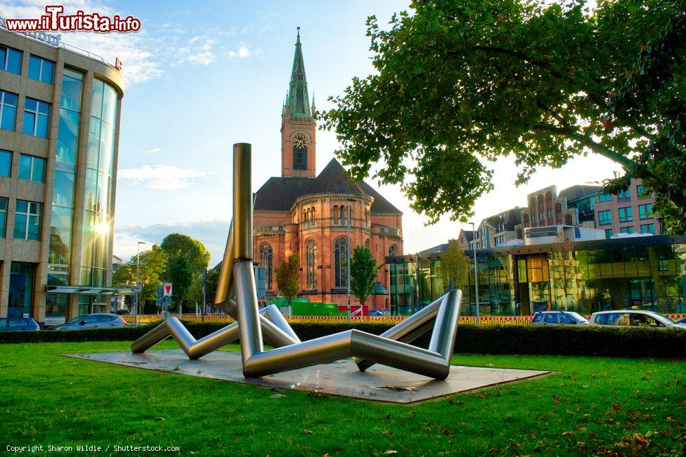 Immagine La chiesa di San Giovanni a Dusseldorf, Germania. E' il più grande edificio di culto protestante della città; di fronte, si trova un'opera d'arte in metallo  - © Sharon Wildie / Shutterstock.com