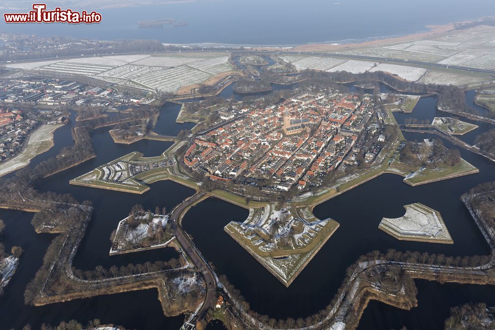 Immagine La città fortificata di Naarden vista in inverno dall'alto, Paesi Bassi. Ricostruita dopo un'alluvione nel 1350, questa cittdina si affermò come importante centro mercantile; nel 1572 venne però invasa dagli spagnoli. Successivamente gli olandesi ripresero il controllo del territorio e iniziarono a fortificarlo. Il risultato è l'incredibile pianta a stella che tutt'oggi rappresenta la caratteristica principale della città.