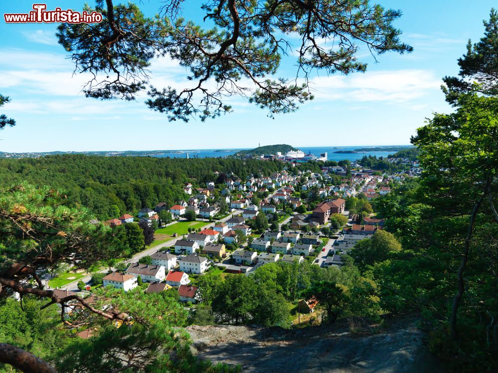 Immagine La città norvegese di Kristiansand vista dall'alto delle colline in una giornata di sole. Il mercato del pesce incastonato nel grazioso porticciolo, il centro storico, i musei, i ristoranti e i parchi gioco per i più piccoli sono alcuni dei luoghi da non perdere durante un tour alla scoperta di questo territorio.