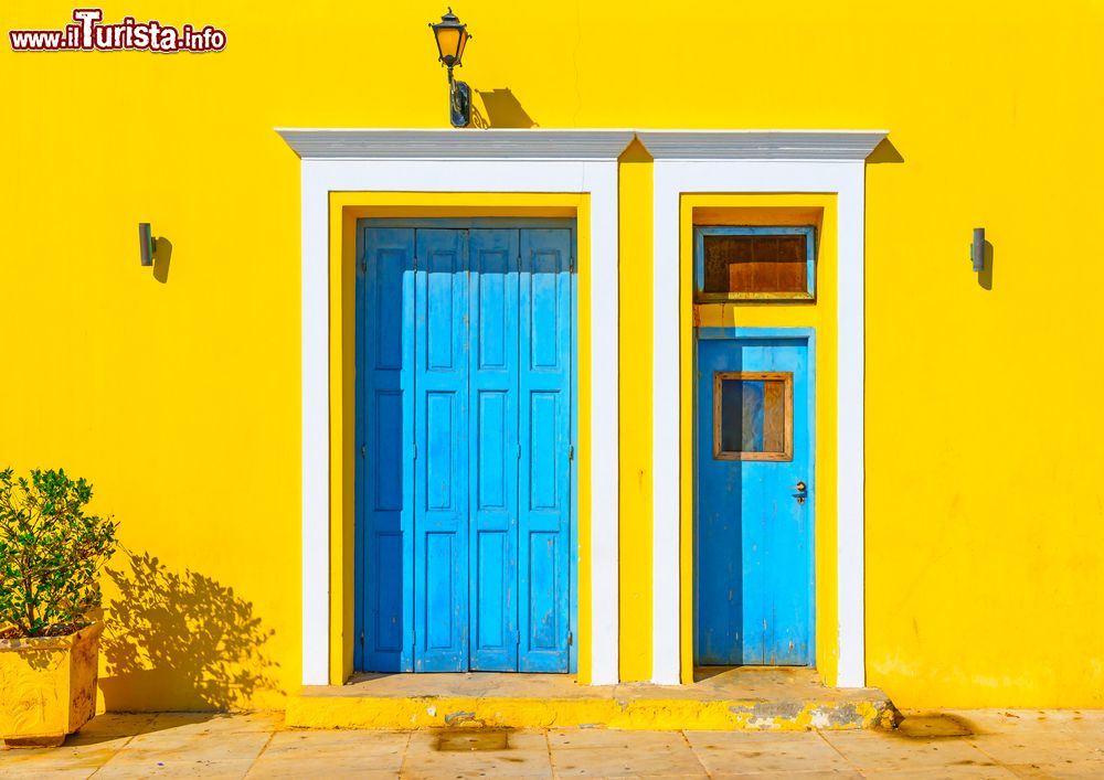 Immagine La colorata facciata di una casa sull'isola di Spetses, Grecia: due porte azzurre impreziosiscono il muro giallo acceso.