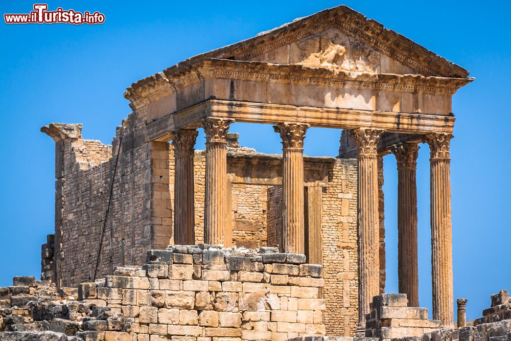 Immagine La facciata del Tempio Capitolino di Dougga, Tunisia. Si tratta di una costruzione con colonne a fusti scanalati sormontati da capitelli in stile corinzio.