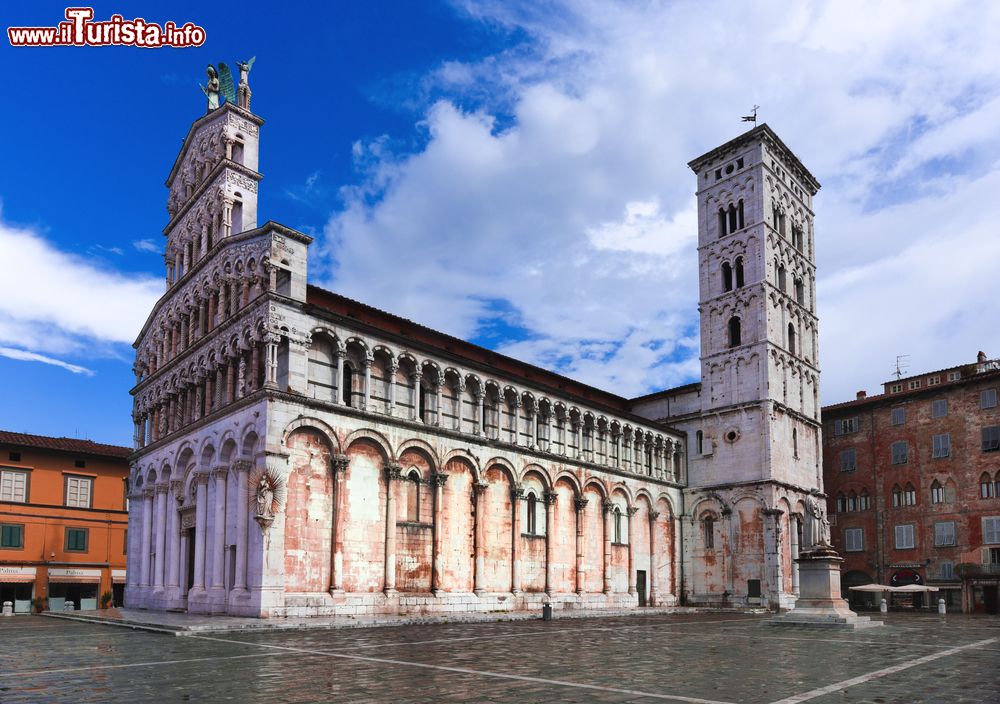 Immagine La facciata romanica della chiesa di San Michele in Foro a Lucca, Toscana. E' situata su un rialzo in pietra delimitato da 4 colonne marmoree collegate da pesanti catene metalliche. Iniziata nell'VIII° secolo, fu completata solo nel XIV° secolo.