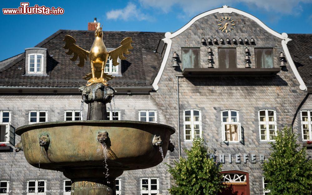 Immagine La fontana nella piazza centrale di Goslar (Germania) con l'aquila imperiale sulla cima. Sullo sfondo, un palazzo con campane e orologio - © pxl.store / Shutterstock.com