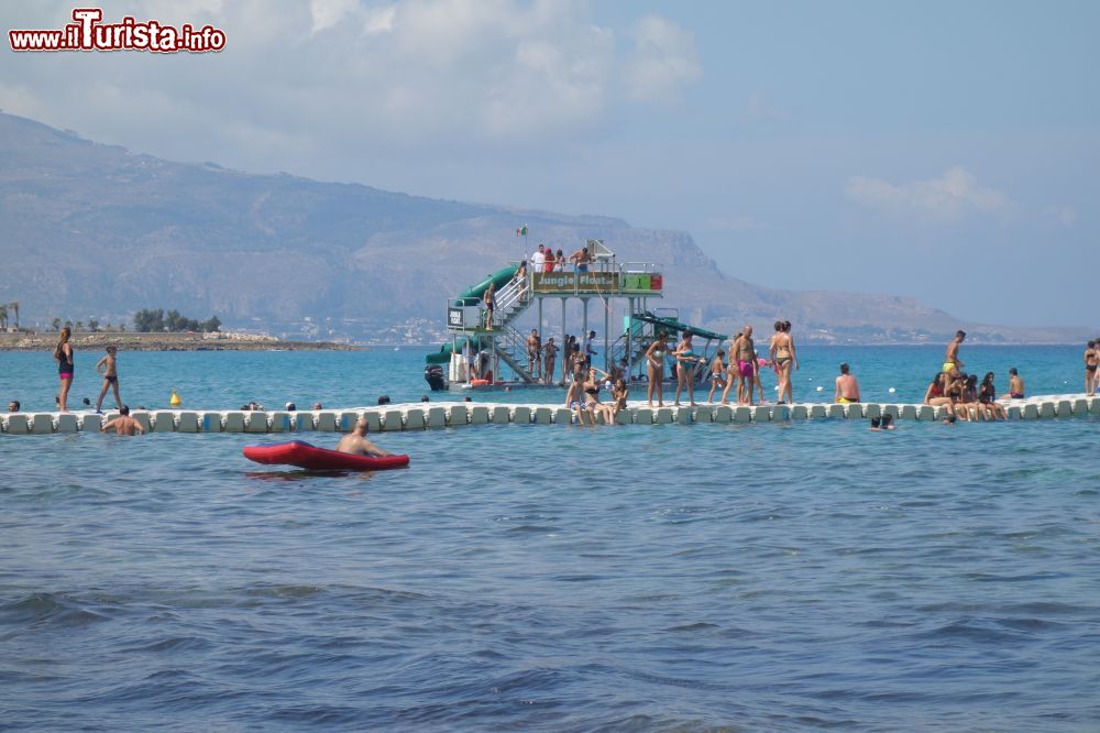 Immagine La grande passerella sul mare della Baia di Cornino, permette di superare un tratto di rocce scivolose e tuffarsi nel mare cristallino senza pericoli. Sullo sfondo la piattaforma per i tuffi.
