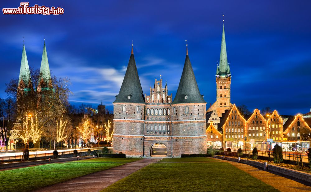 Immagine La Holstentor illuminata di notte con decorazioni natalizie, Lubecca, Germania.