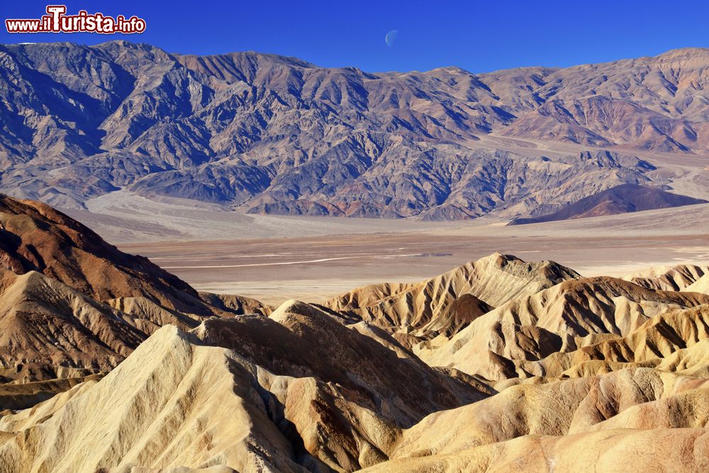 Immagine La luna fotografata sopra Zabriskie Point nel parco nazionale della Death Valley, California. Questo luogo si trova 7 chilometri dopo Furnace Creek, sulla Highway 190 in direzione Death Valley Junction. La roccia sembra essere fatta di spuma.