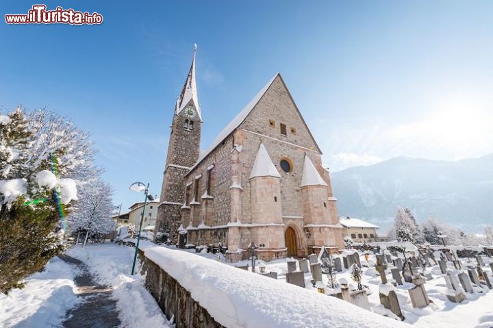 Immagine La neve sulla Chiesa dei SS. Wolfgang e Leonhard a Jenbach, Tirolo - questa splendida chiesa di montagna, piccola ma riccamente decorata, emana un incredibile fascino storico, riportandoci indietro agli antichi tempi in cui fu costruita. Se l'esterno in pietra ci rimanda immediatamente alle costruzioni montanare, l'interno sorprende con le sue fini decorazioni e i suoi elementi di bell'artigianato tirolese. 