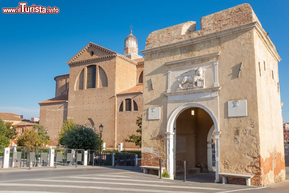 Immagine La porta di Santa Maria e l'omonima cattedrale a Chioggia, Veneto, Italia. Questa porta d'ingresso alla città, nei cui pressi sorge la cattedrale, ha una struttura ad arco che risale al 1530 e in origine faceva parte della fortificazione cittadina. Attraverso Santa Maria, così chiamata probabilmente per un capitello in onore della Madonna situato al suo interno, si entra nel Corso del Popolo, la principale strada di Chioggia.