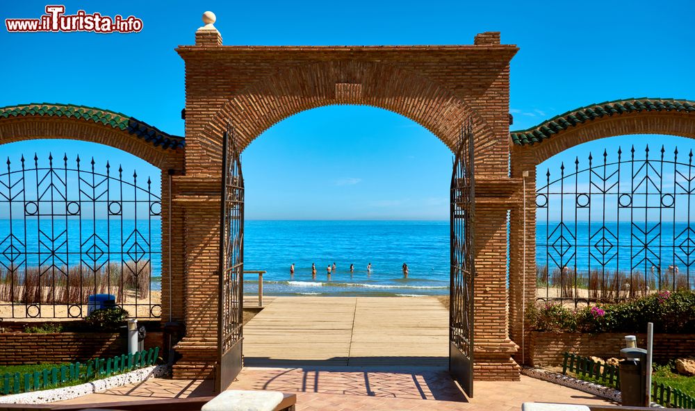 Immagine La spiaggia di Marina d'Or vista attraverso gli archi del cancello d'ingresso, Spagna. A lambire le coste di questo tratto litoraneo del sud spagnolo sono le acque trasparenti e azzurro intenso del mar Mediterraneo