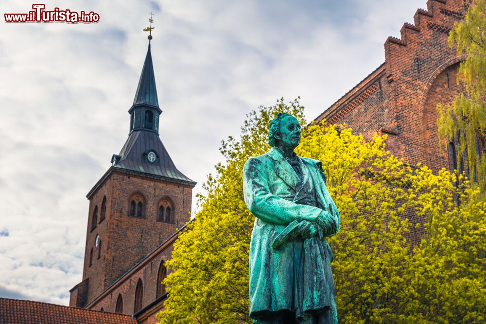 Immagine La statua di Andersen con la cattedrale di San Canuto sullo sfondo, Odense, Danimarca. L'edificio religioso è stato chiamato così in onore del re danese Canuto il Santo.