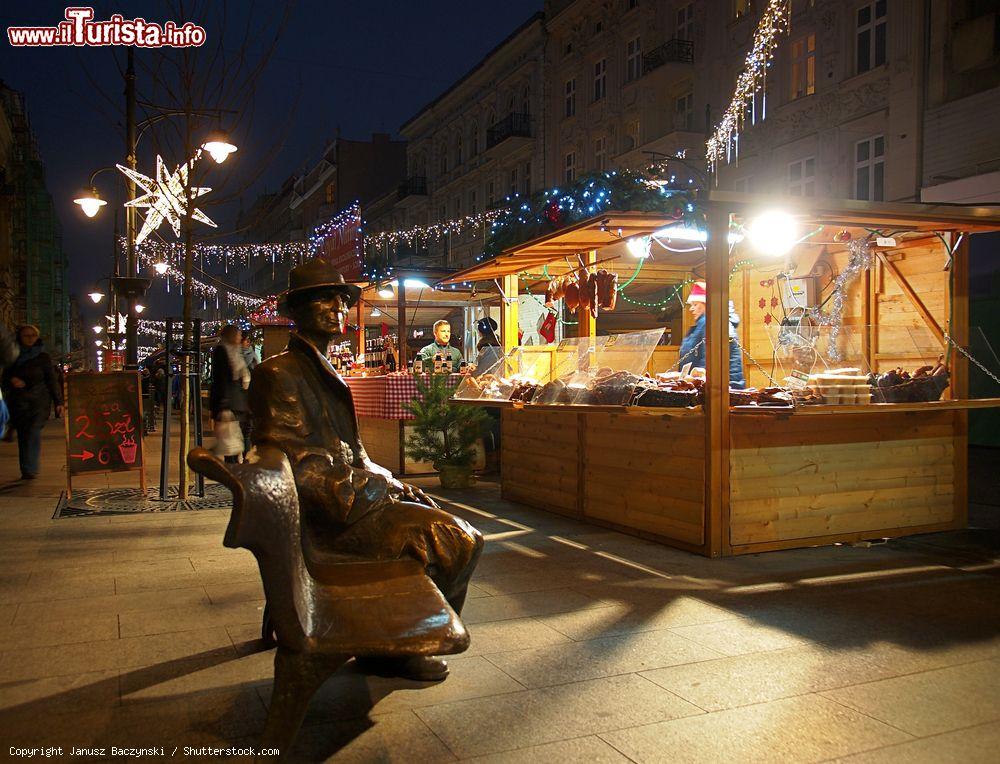 Immagine La statua di Julian Tuwim e la fiera di Natale a Lodz, Polonia. Il monumento "La panchina di Tuwim" con le bancarelle natalizie illuminate in occasione delle festività in Piotrkowska Street - © Janusz Baczynski / Shutterstock.com