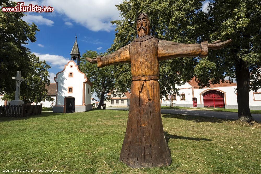 Immagine La statua in legno nella piazza centrale di Holasovice, Repubblica Ceca. Sullo sfondo la cappella e le abitazioni del paese - © Fulcanelli / Shutterstock.com