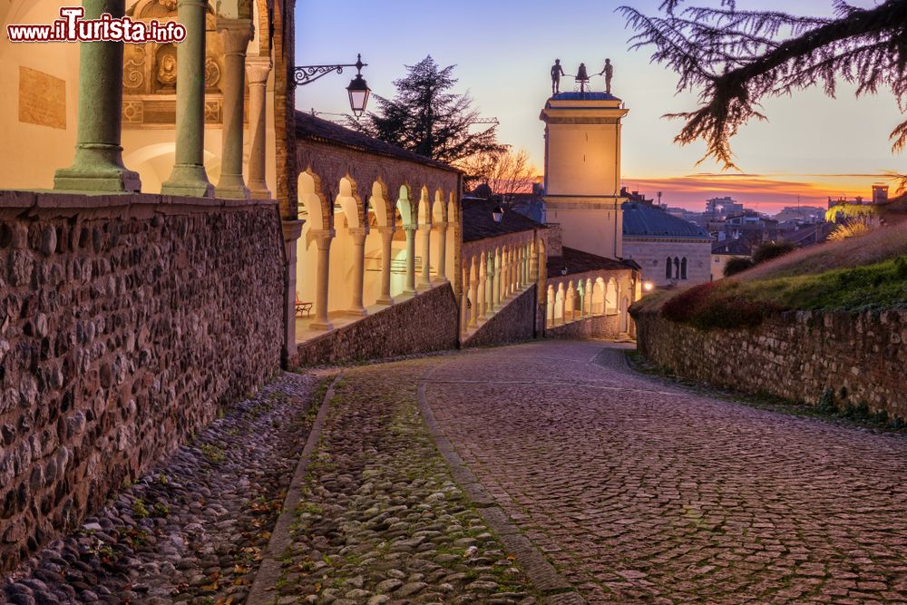 Immagine Le colonne del castello di Udine illuminate di notte, Friuli Venezia Giulia. La strada che fiancheggia la fortezza è ciottolata.