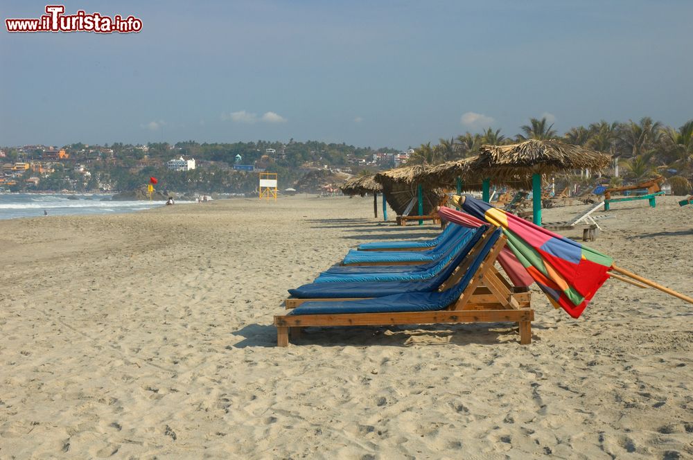 Immagine Lettini e ombrelloni colorati su una spiaggia deserta di Puerto Escondido, Messico.