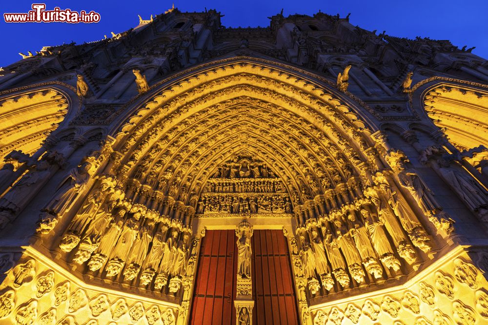 Immagine Lo splendido portale principale della cattedrale di Our Lady di Amiens, Francia. Fotografato di notte e illuminato, il grande portale si presenta con una ricca decorazione scultorea e con la statua di Cristo in atteggiamento maestoso (nota anche come Beau Dieu) e con la scena del Giudizio universale nel timpano.