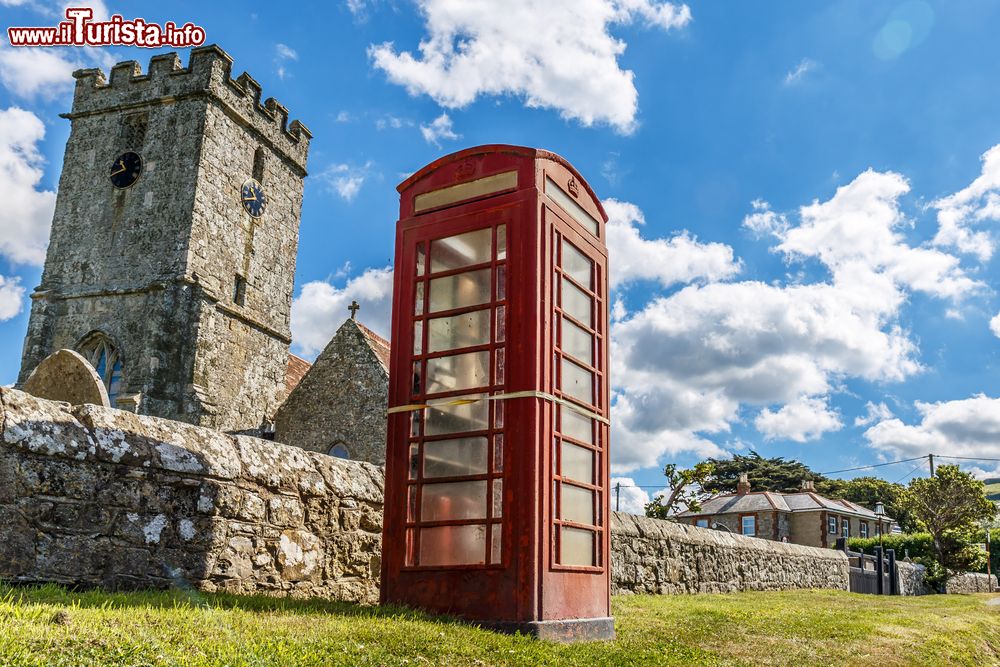 Immagine Moderno e antico sull'isola di Wight, Inghilterra: una cabina telefonica e una chiesa in pietra.