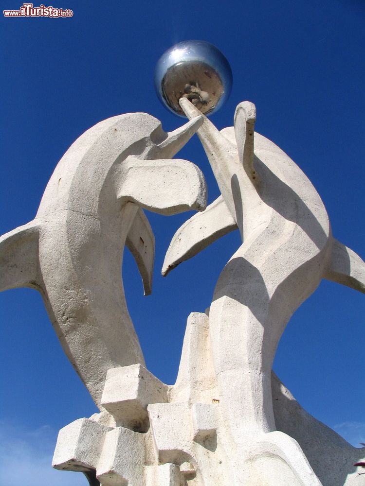 Immagine Monumento sulla spiaggia di Qingdao, Cina: due delfini in pietra giocano con una sfera.