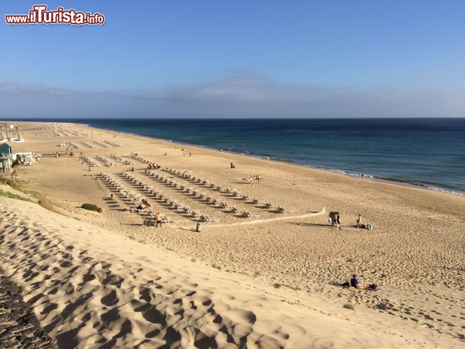 Immagine Distesa di sabbia bianca di Jandia Playa (o Morro Jable) a Fuerteventura, Spagna - Alcuni turisti prima di recarsi in questa parte di Fuerteventura, ossia quella situata più a sud, si informano circa la situazione dei venti. Ebbene nella spiaggia di Morro Jable ci si trova nella zona più riparata in questo senso, inoltre le strutture montano appositi frangivento per non sollevare la sabbia. Per cui, guardando quest'immagine, non bisogna assolutamente temere: una volta recatisi nelle strutture adatte, queste forniranno ogni elemento necessario per un ottimo soggiorno.