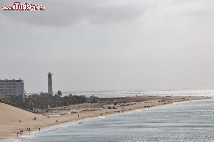 Immagine Il faro del litorale di Morro Jable, Fuerteventura, Spagna - In quest'immagine spicca tutto di questa bellissima parte di costa situata nella parte più a sud di Fuerteventura. Si vede perfettamente la lunga distesa di sabbia bianca, così come si intravedono i palazzi alti che corrispondono ad hotel e strutture turistiche e infine, ultimo ma non per importanza, il faro che si affaccia sul mare e regala una vista spettacolare.