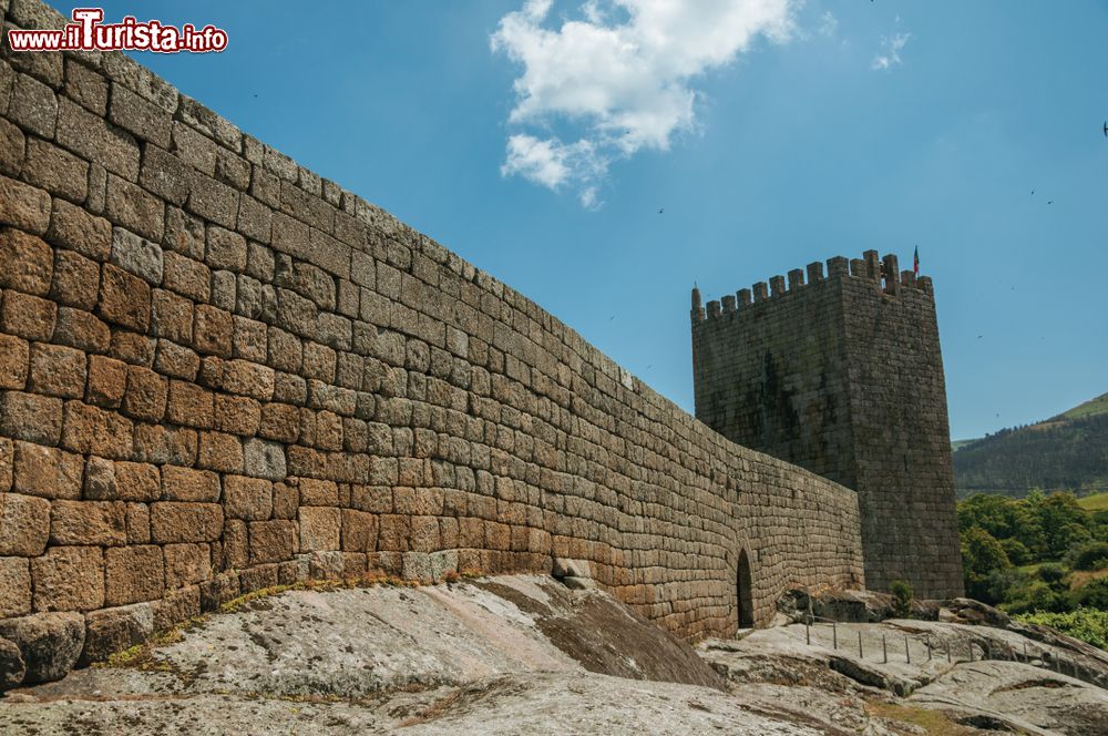 Immagine Mura in pietra e torre sulle alture del borgo di Linhares da Beira, Portogallo, fotografate in una giornata estiva di sole.
