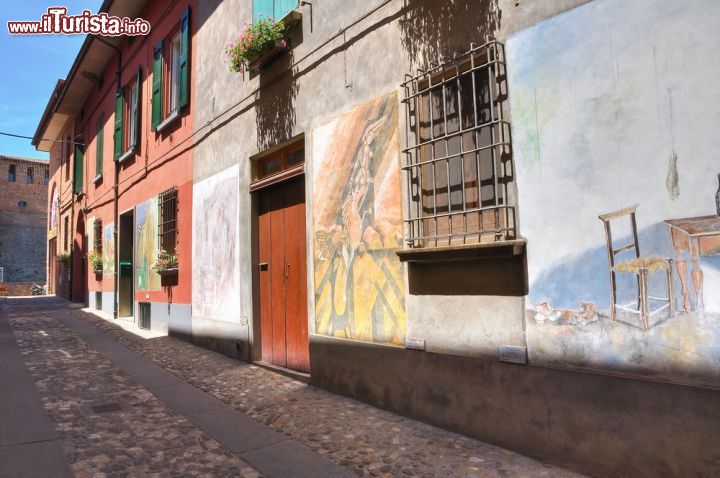 Immagine Tra la porta d'ingresso e la Rocca Sforzesca, all'interno di un dedalo di viuzze, si trovano un centinaio di murales dipinti direttamente sulle facciate delle abitazioni. Hanno dimensioni differenti, temi e colori molti diversi fra di loro ma tutti si inseriscono fra le finestre e circondano le porte amalgamandosi perfettamente con il tessuto urbano di Dozza. Già impreziosito dal suo bel castello, questo borgo medievale ha dato una svolta importante alla propria storia nel 1960 quando si è trasformato in una galleria a cielo aperto dove gli artisti della "street art" si danno appuntamento ogni due anni per esprimere la propria creatività - © Mi.Ti. / Shutterstock.com