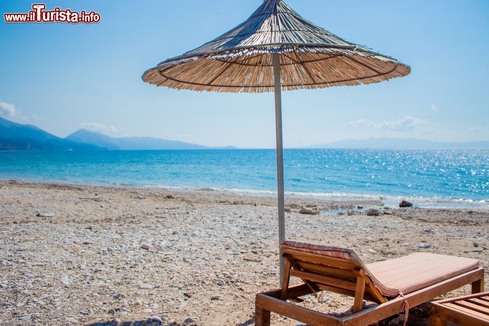 Immagine Ombrellone e lettino sulla spiaggia di Qeparo, con sabbie, ciottoli e mare pulito.