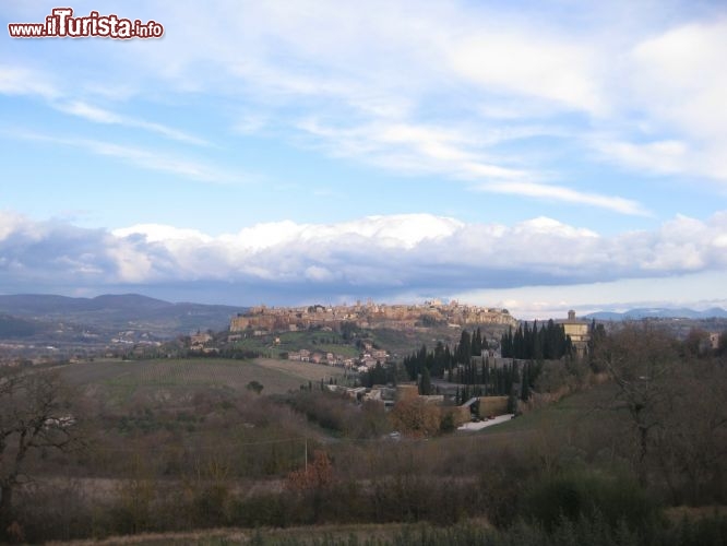 Immagine Orvieto come si ammira dalle colline della provincia di Terni in Umbria. Il borgo si erge sul un affioramento di tufo che domina la valle del Tevere. La roccia, pur abbastanza friabile, ha creato delle pareti verticali di roccia, e la cittadina si viene trovare protetto da una cinta muraria, totalmente naturale