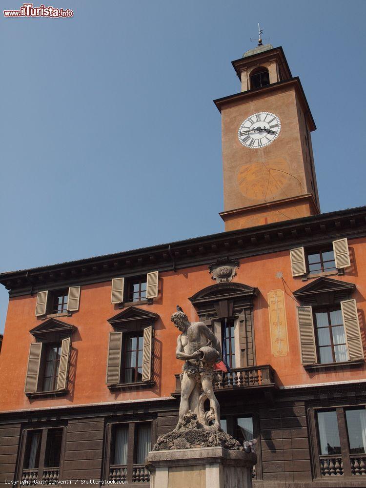 Immagine Palazzo del Monte in Piazza del Duomo a Reggio Emilia con la fontana del fiume Crostolo, Emilia Romagna. Sede del Comune sino al 1494, questo edificio è stato successivamente occupato dal Monte di Pietà e altre strutture pubbliche. A sormontarlo, con i suoi 47 metri, è la torre dell'orologio con l'originaria torre merlata del 1216 - © Gaia Conventi / Shutterstock.com