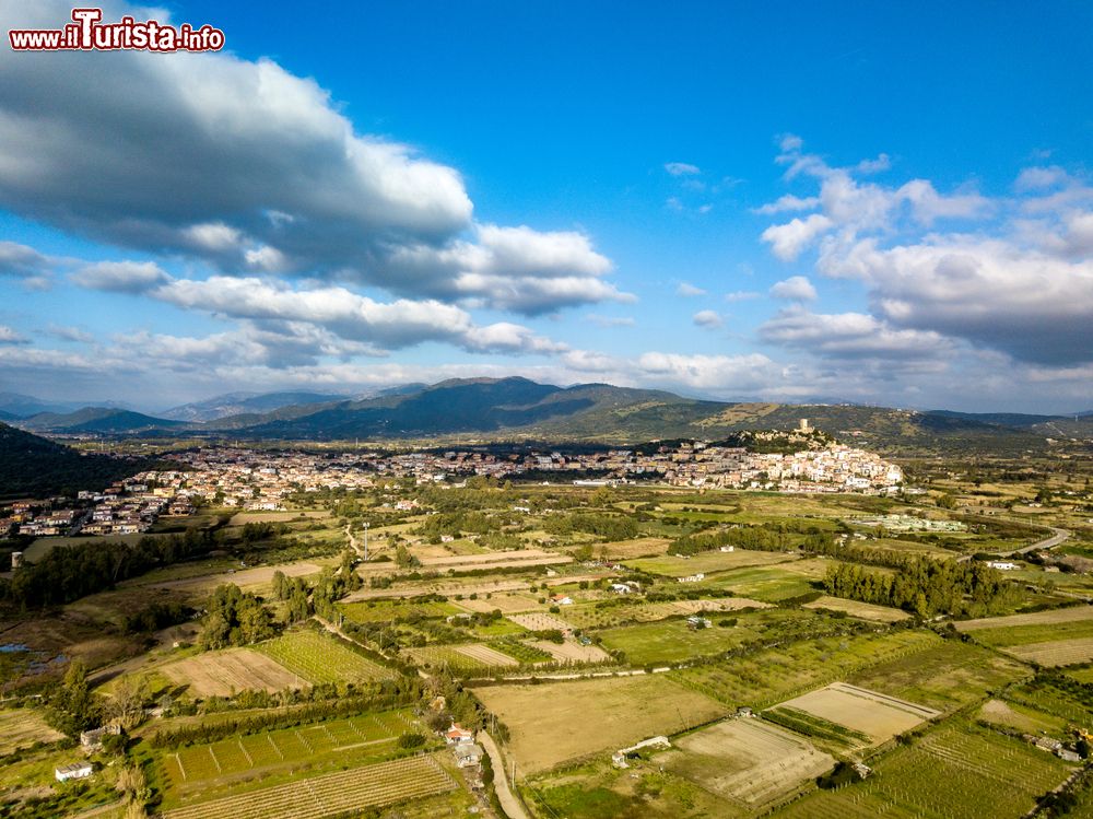 Immagine Panorama aereo di Posada, borgo della Baronia, Sardegna. Arroccato su una rupe, questo villaggio è dominato da un castello e ai suoi piedi si estende una valle verde che sfocia nel fiume turchese.