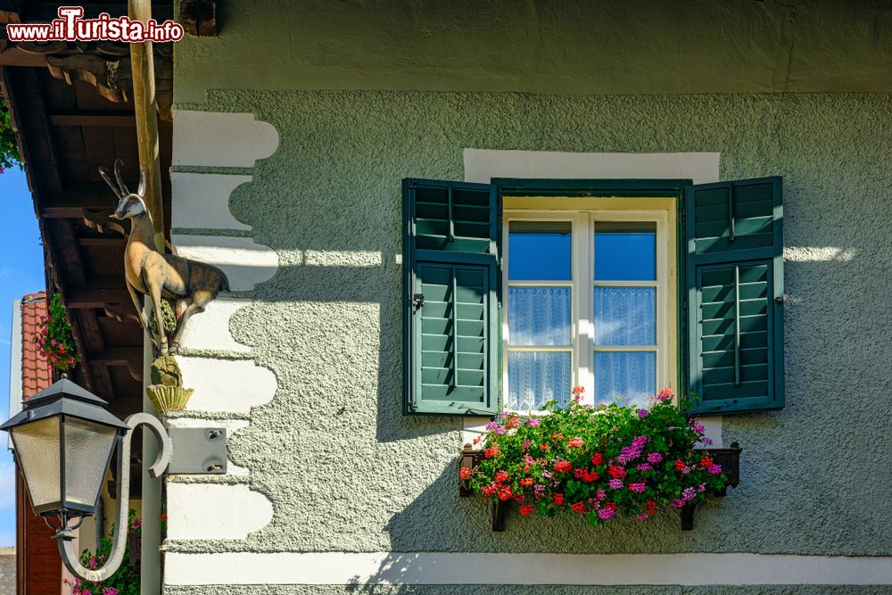 Immagine Particolare di una casa residenziale a Gmuend in Kaernten, distretto di Spittal an der Drau: una finestra con persiane in legno e fiori colorati.