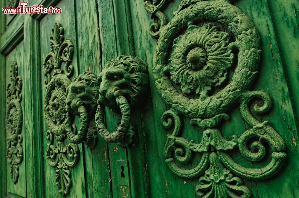 Immagine Particolare di un'antica porta in legno nella città di Venafro, Molise. I batacchi a forma di leone impreziosiscono questa porta d'ingresso decorata.